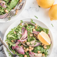 spinach and arugula salad in a white bowl with lemon