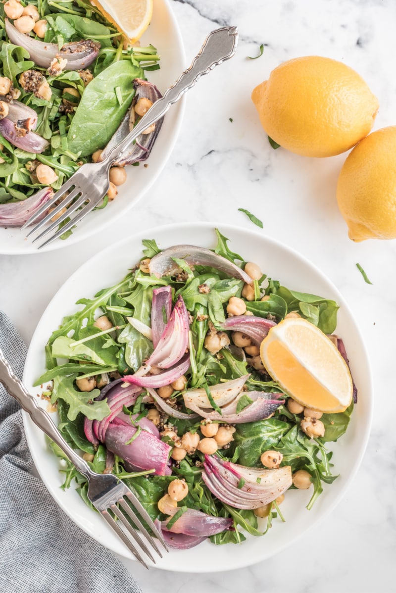 spinach and arugula salad in a white bowl with lemon