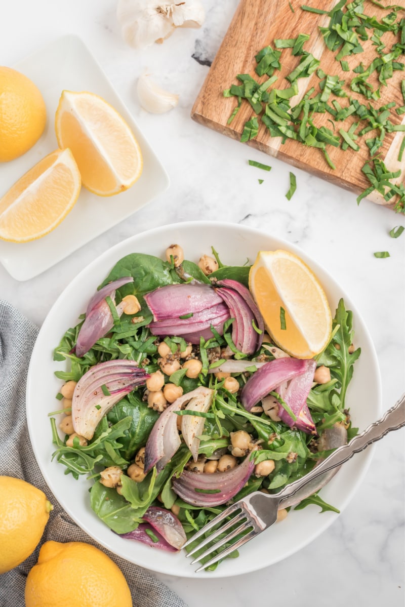 spinach and arugula salad in a white bowl with lemon
