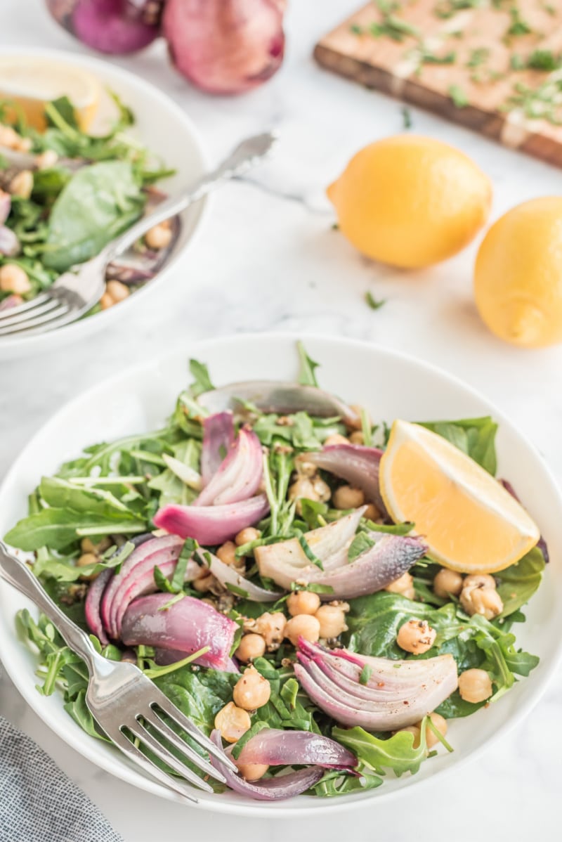 spinach and arugula salad in a white bowl with lemon