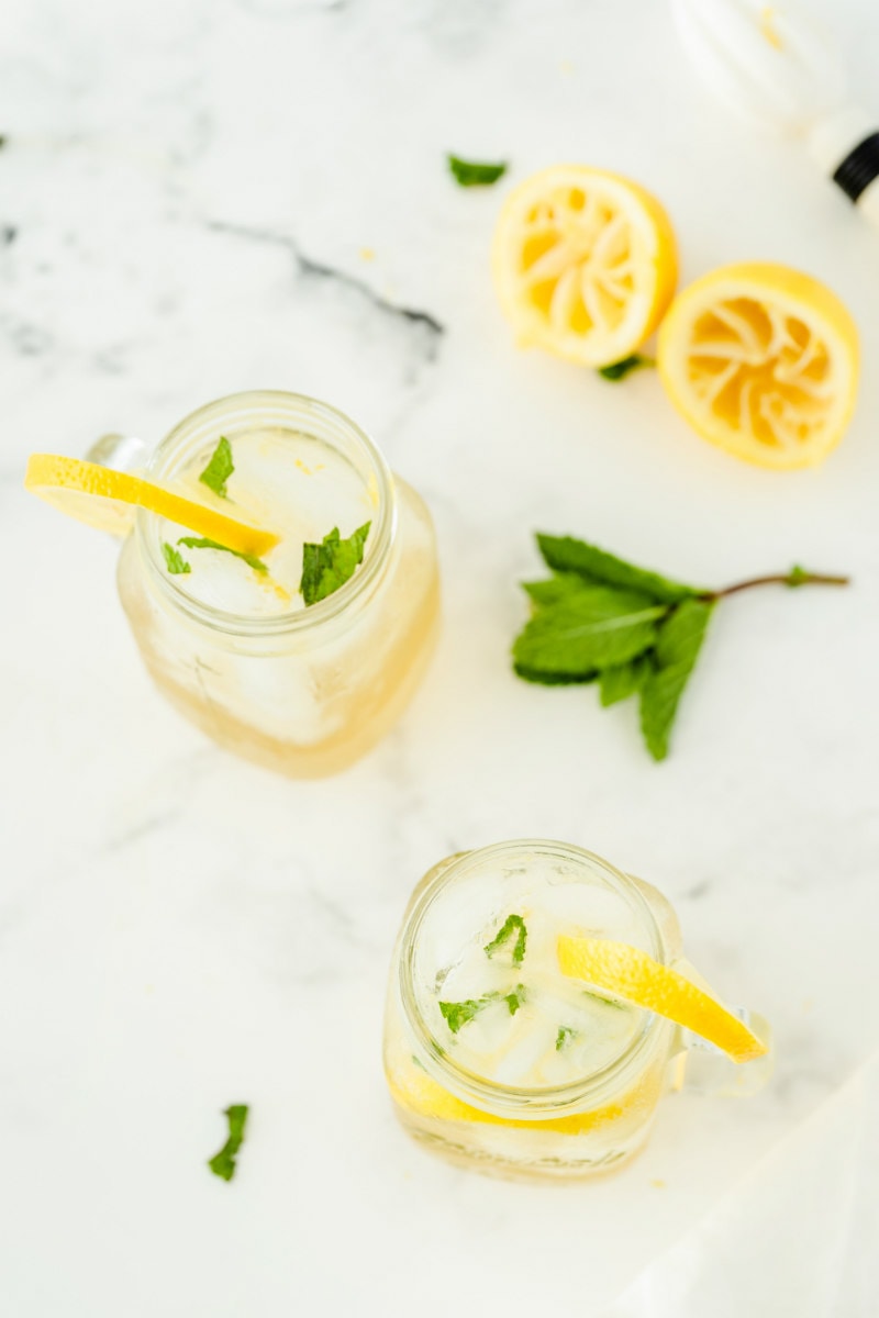 overhead shot of glasses of vodka lemonade with squeezed lemons and fresh mint in background