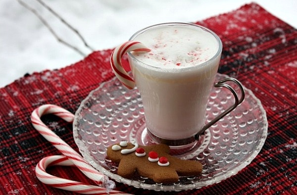 mug of white chocolate and peppermint hot chocolate on a plate with a cookie and candy canes