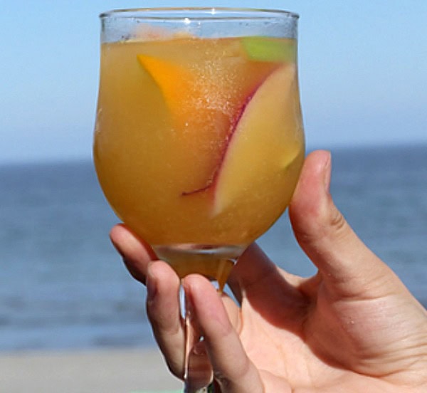 hand holding glass of peach sangria