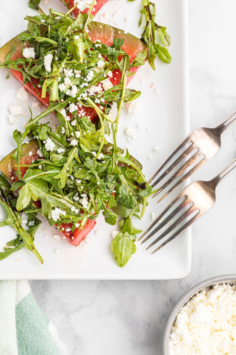 grilled watermelon salad on a white platter with two forks