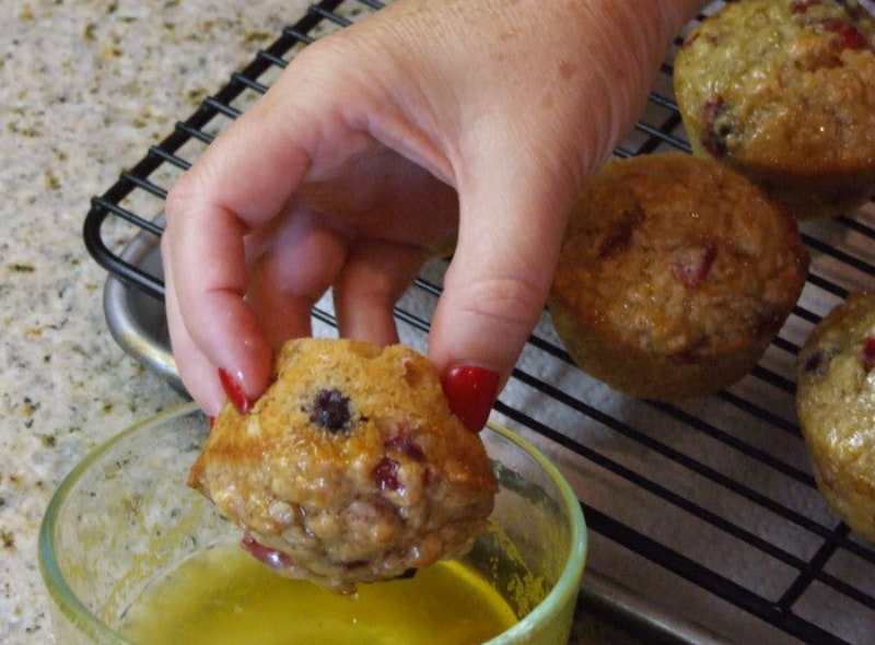 dipping top of muffin in orange glaze