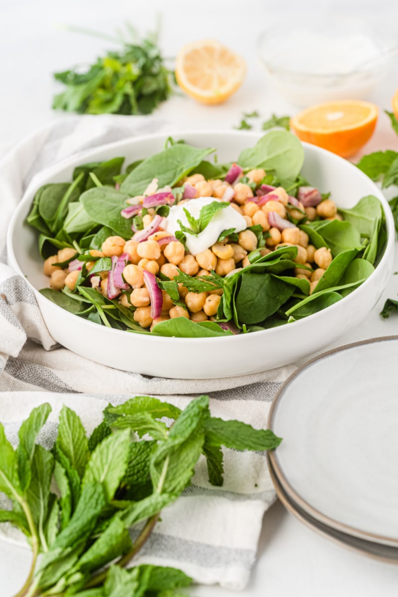chickpea and spinach salad in bowl topped with creamy cumin dressing