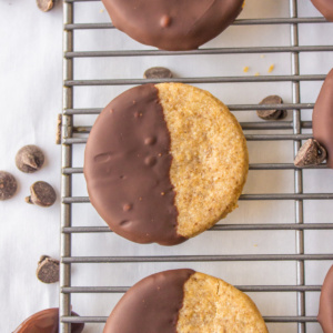 three half chocolate dipped cookies on a cooling rack