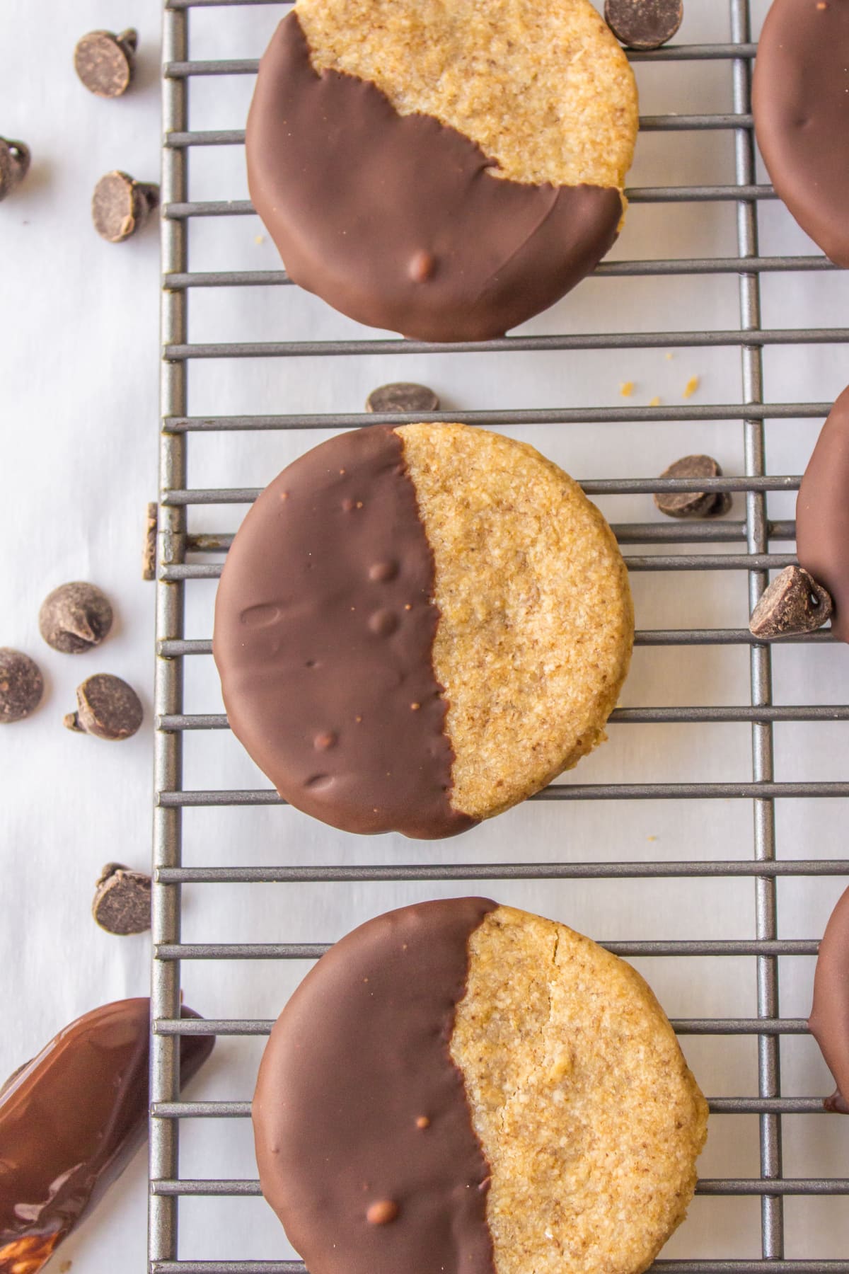 three half chocolate dipped cookies on a cooling rack 