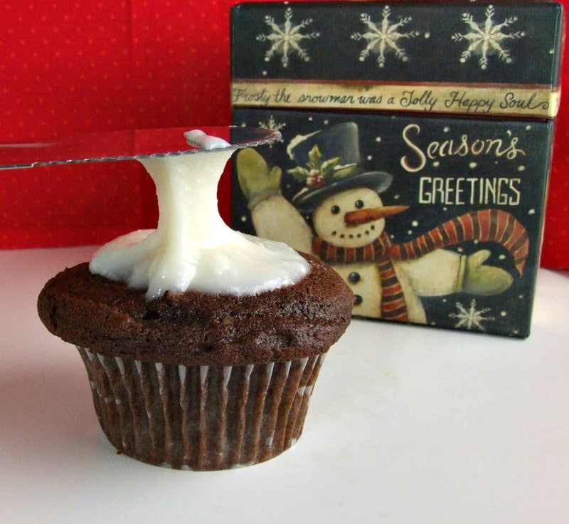 adding peppermint icing to chocolate cupcake