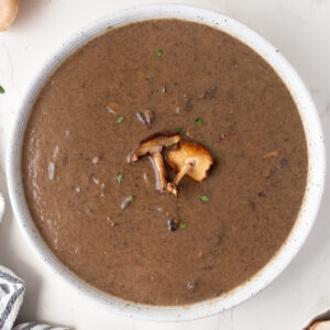 big bowl of roasted mushroom soup garnished with fresh mushrooms