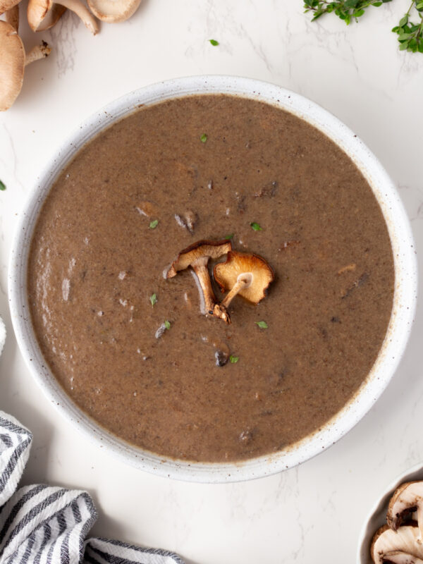 big bowl of roasted mushroom soup garnished with fresh mushrooms