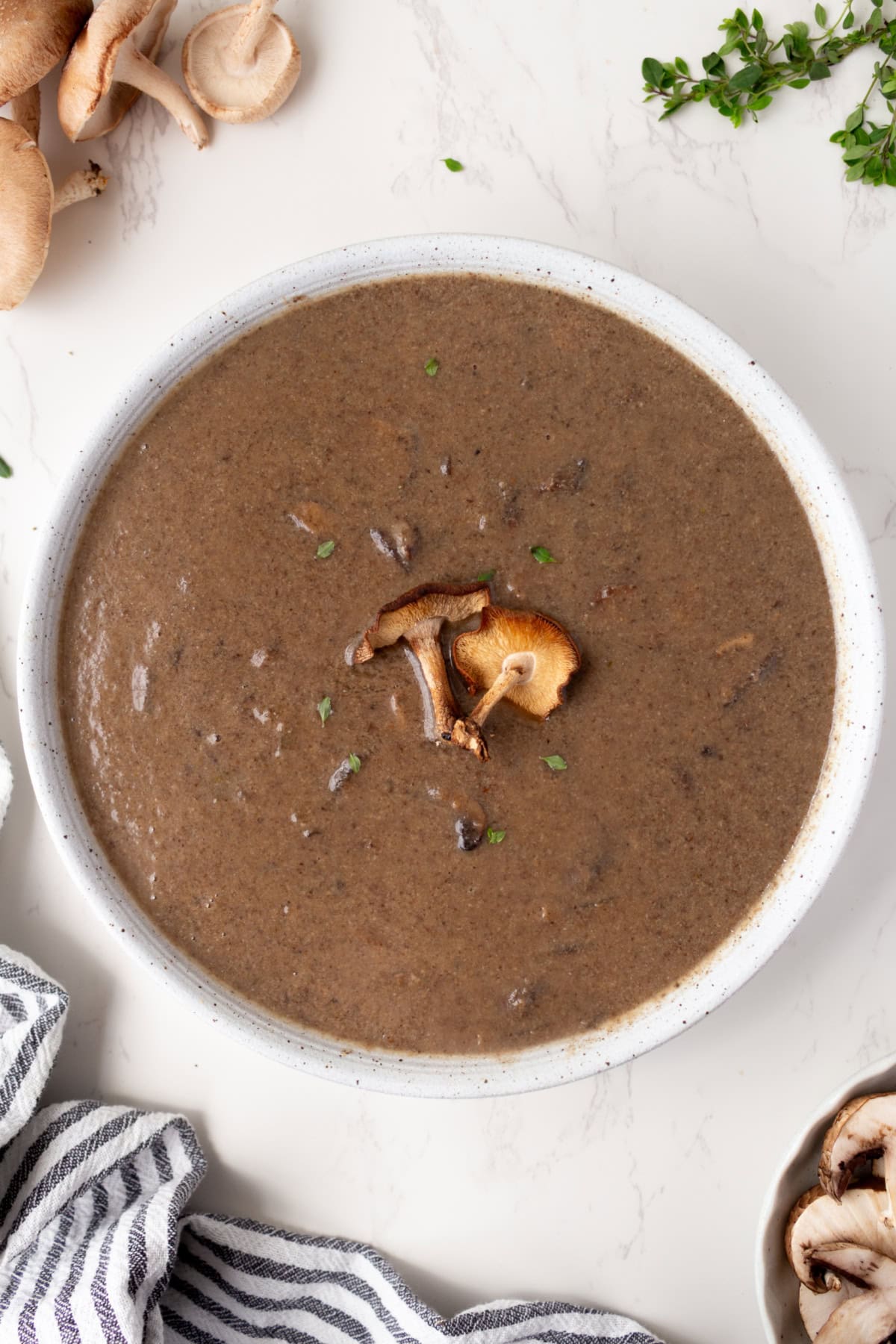 If you love mushrooms, you need to try this Roasted Mushroom Soup! Shiitake and cremini mushrooms are roasted to bring out their rich, earthy flavor, then combined with white wine, fresh thyme and a touch of cream. A delicious homemade soup for fall, winter or any cozy dinner! big bowl of roasted mushroom soup garnished with fresh mushrooms