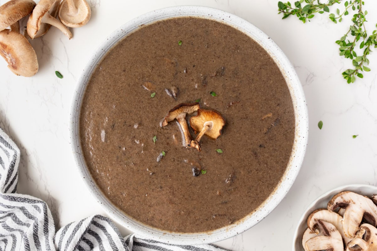 If you love mushrooms, you need to try this Roasted Mushroom Soup! Shiitake and cremini mushrooms are roasted to bring out their rich, earthy flavor, then combined with white wine, fresh thyme and a touch of cream. A delicious homemade soup for fall, winter or any cozy dinner! white bowl filled with roasted mushroom soup