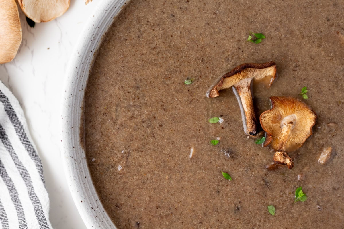 If you love mushrooms, you need to try this Roasted Mushroom Soup! Shiitake and cremini mushrooms are roasted to bring out their rich, earthy flavor, then combined with white wine, fresh thyme and a touch of cream. A delicious homemade soup for fall, winter or any cozy dinner! bowl of roasted mushroom soup garnished with mushrooms