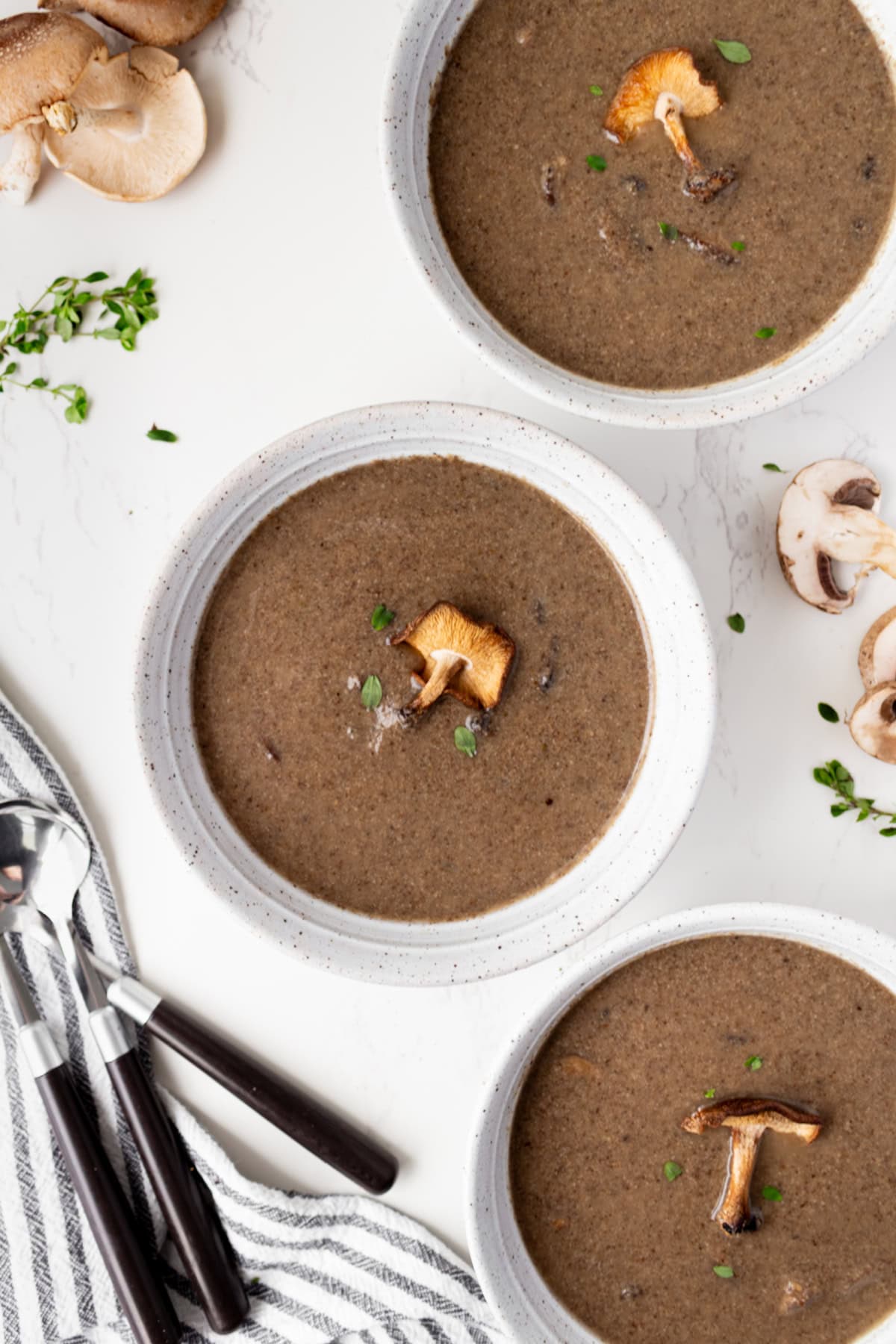 If you love mushrooms, you need to try this Roasted Mushroom Soup! Shiitake and cremini mushrooms are roasted to bring out their rich, earthy flavor, then combined with white wine, fresh thyme and a touch of cream. A delicious homemade soup for fall, winter or any cozy dinner! three bowls of roasted mushroom soup