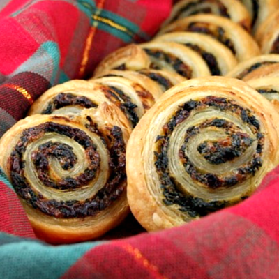 spinach and sundried tomato puff pastries in plaid napkin lined basket