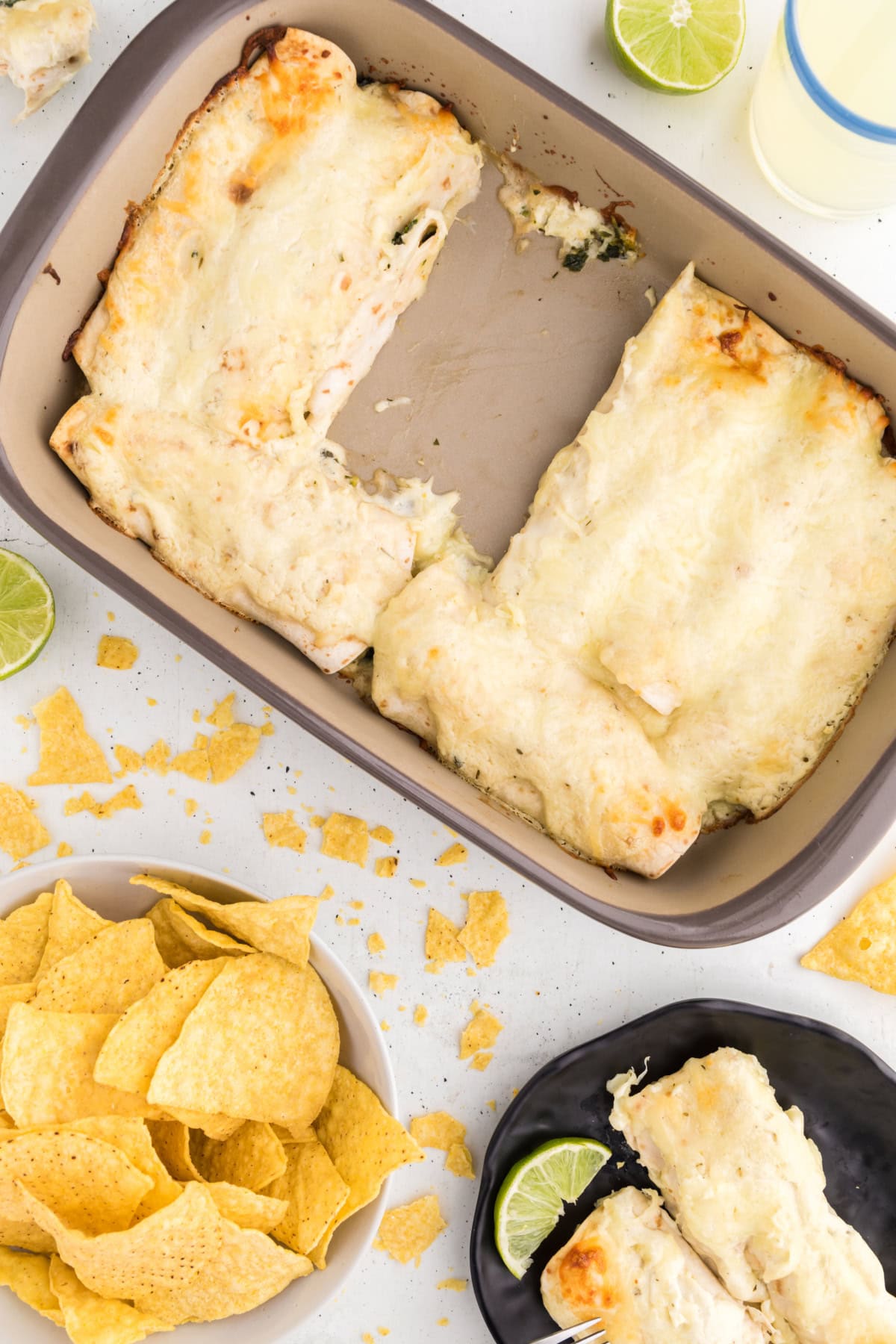 overhead shot of pan of creamy chicken enchiladas with serving on plate