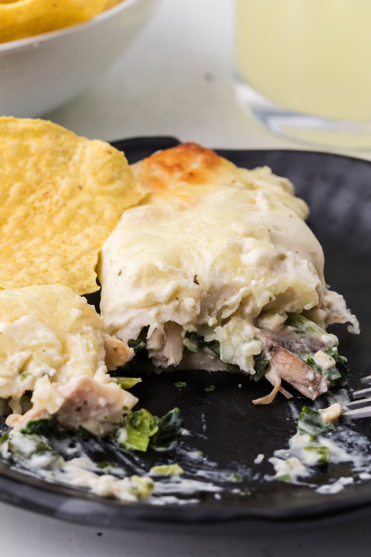 serving of creamy chicken spinach and mushroom enchiladas on plate cut into