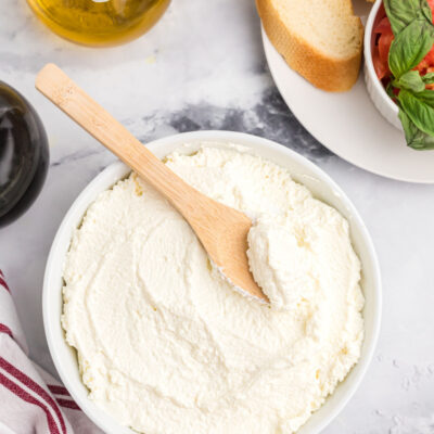 bowl of homemade ricotta cheese with wooden spoon