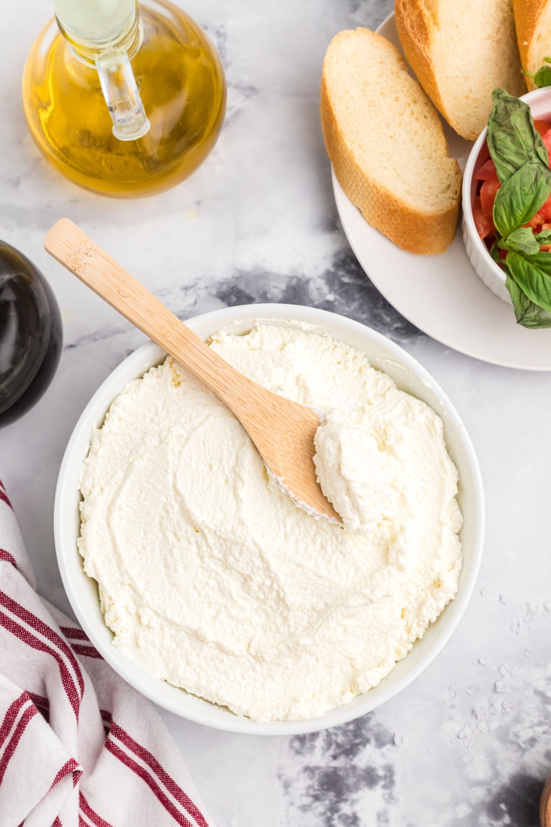 bowl of homemade ricotta cheese with wooden spoon