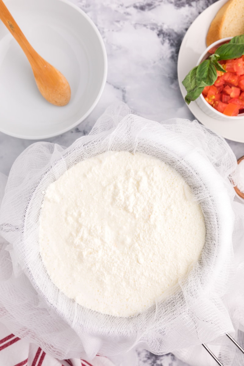 cheesecloth set over bowl and liquid draining through to make ricotta cheese