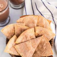 cinnamon bunuelos in a basket with hot chocolate