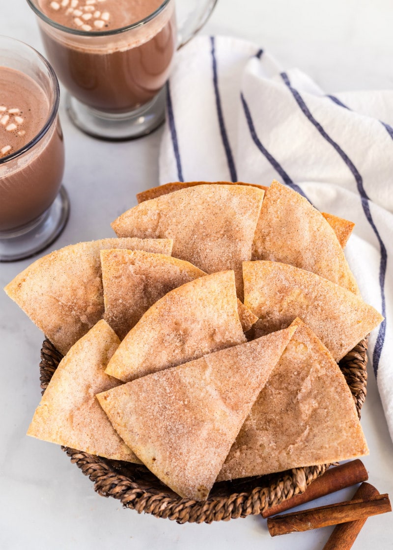 cinnamon bunuelos in a basket with hot chocolate