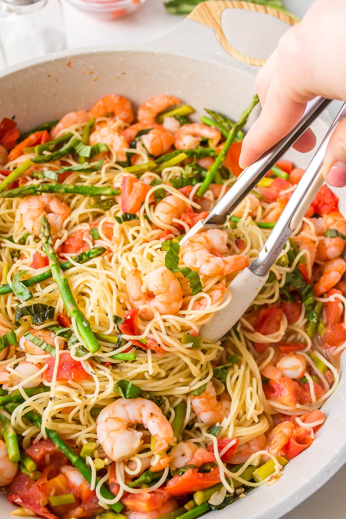 tongs picking up angel hair pasta with shrimp