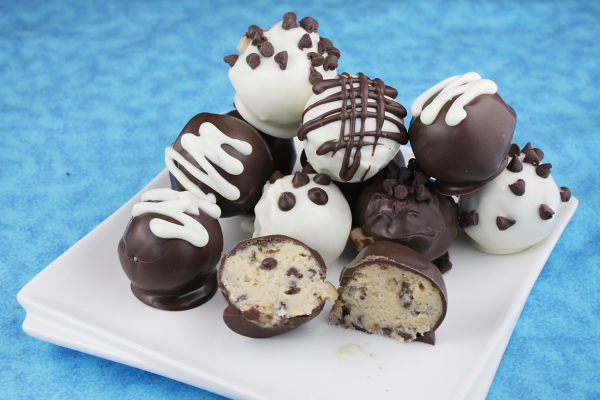 Truffes de pâte à biscuits aux pépites de chocolat sur un plateau blanc avec. l'une d'entre elles coupée en deux