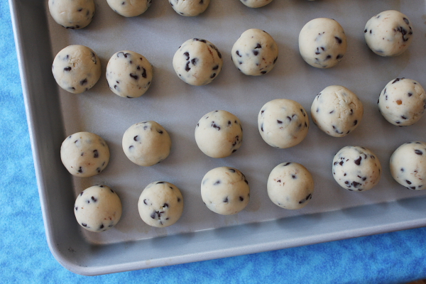 Chocolate Chip Cookie Dough Balls on a baking sheet with a blue background