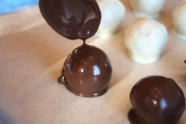 Chocolate Chip Cookie Dough Truffles just melted in chocolate set on a baking sheet