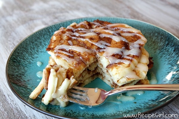 forkful of cinnamon roll pancakes with cream cheese drizzle on a teal green plate