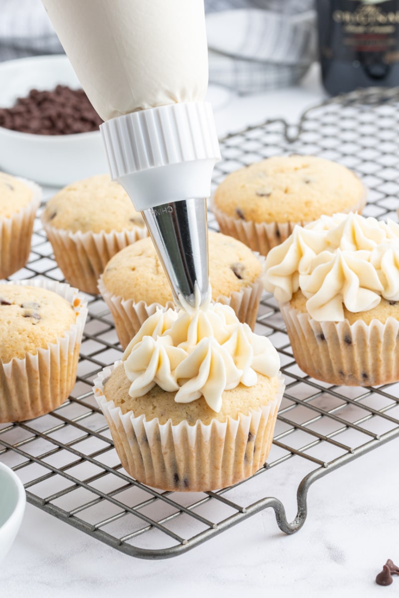 piping baileys buttercream frosting onto irish cream cupcakes