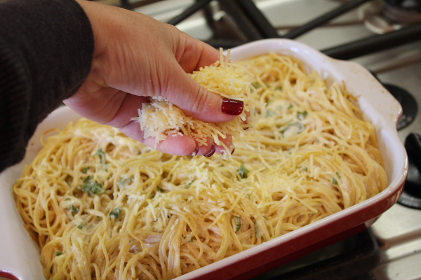 Baked Lemon Spaghetti 14 sprinkling cheese on top of pasta in dish