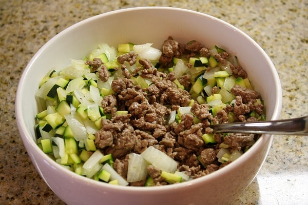 cooked ground beef, zucchini and onion in a white bowl