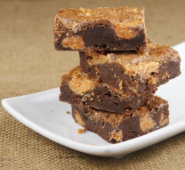 Butterfinger Brownies stacked on a white plate