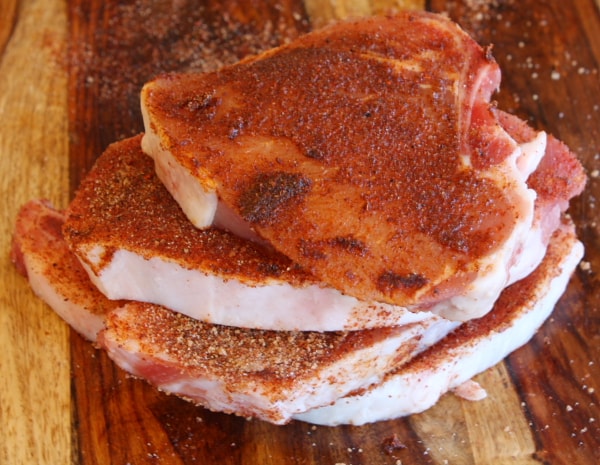 stack of seasoned pork chops on a cutting board