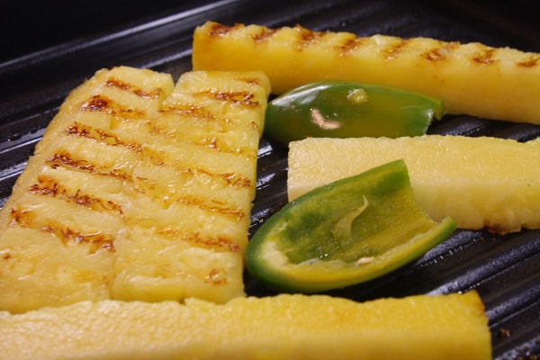 grilling pineapple and jalapeno on a stovetop grill