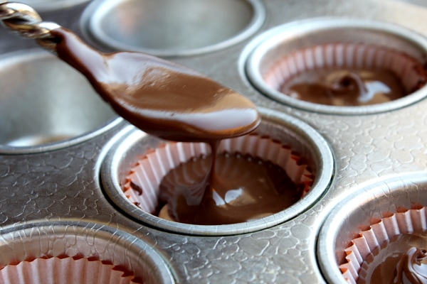Spooning chocolate into cups to make almond butter cups