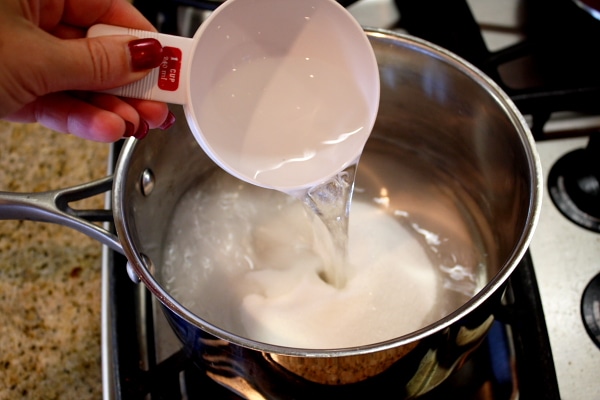 adding vinegar to a pan with a measuring cup