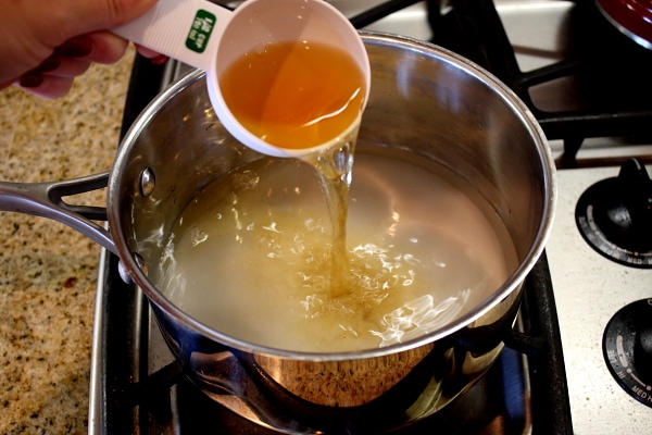 adding vinegar to a pan with a measuring cup