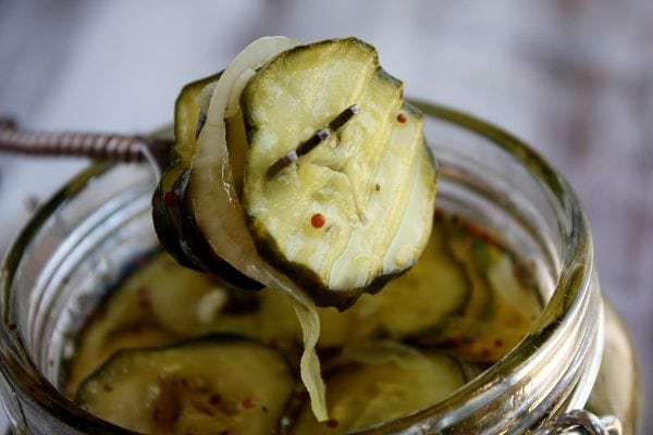 fork full of bread and butter pickles raised just above the opening of the jar