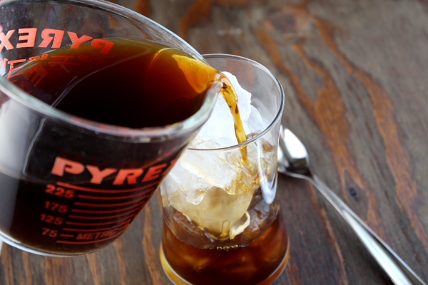 pouring coffee into a glass of ice to make iced coffee