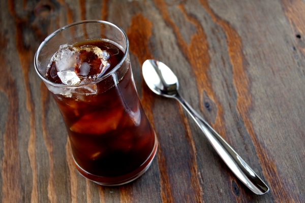 iced coffee sitting on a wooden board with a spoon alongside