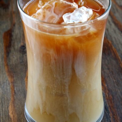 tall glass of iced coffee sitting on a wooden board