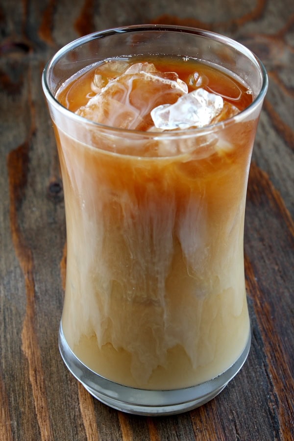 tall glass of iced coffee sitting on a wooden board