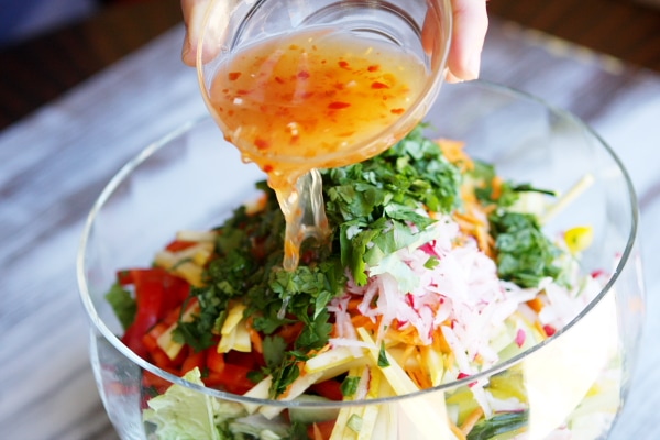 Thai Summer Salad recipe from RecipeGirl.com Pouring dressing onto Thai Summer Salad