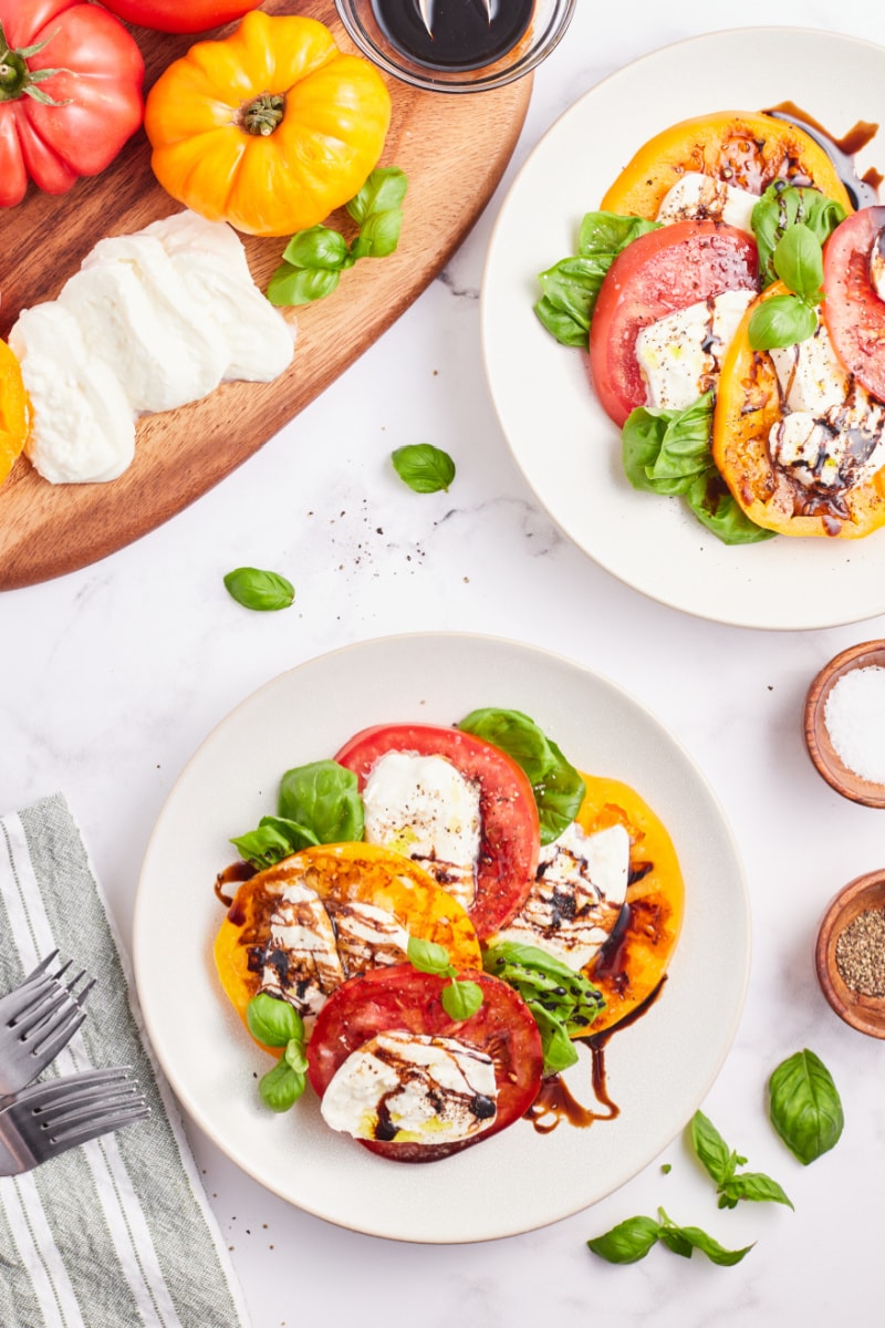 two plates of caprese salad with burrata cheese