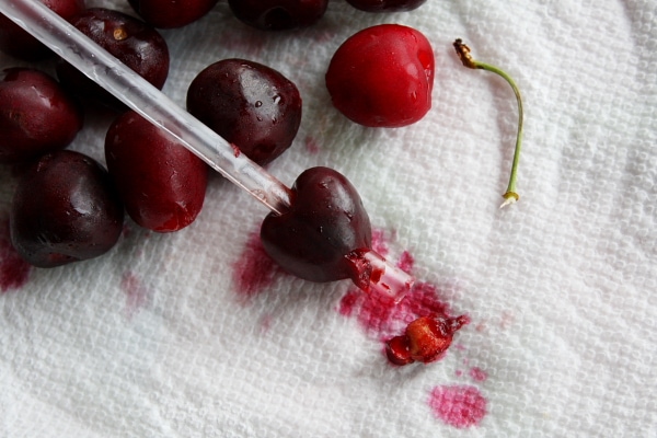 Showing how to Pit Cherries by sticking a straw through the cherry on a paper towel