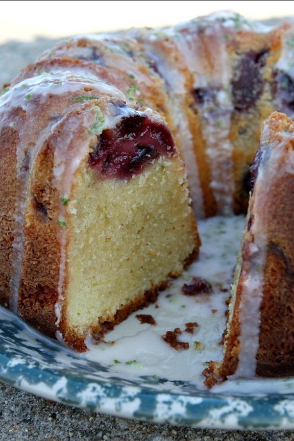 Peeking into the inside of Cherry Limeade Pound Cake that has been sliced open. Set on a blue and white patterned plate.